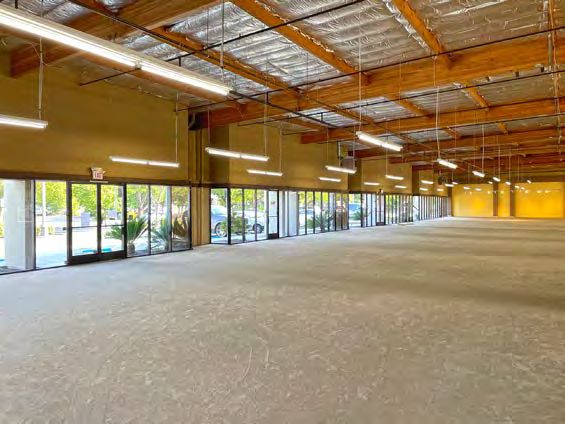 Open floor of the former retail showroom under exposed roof framing